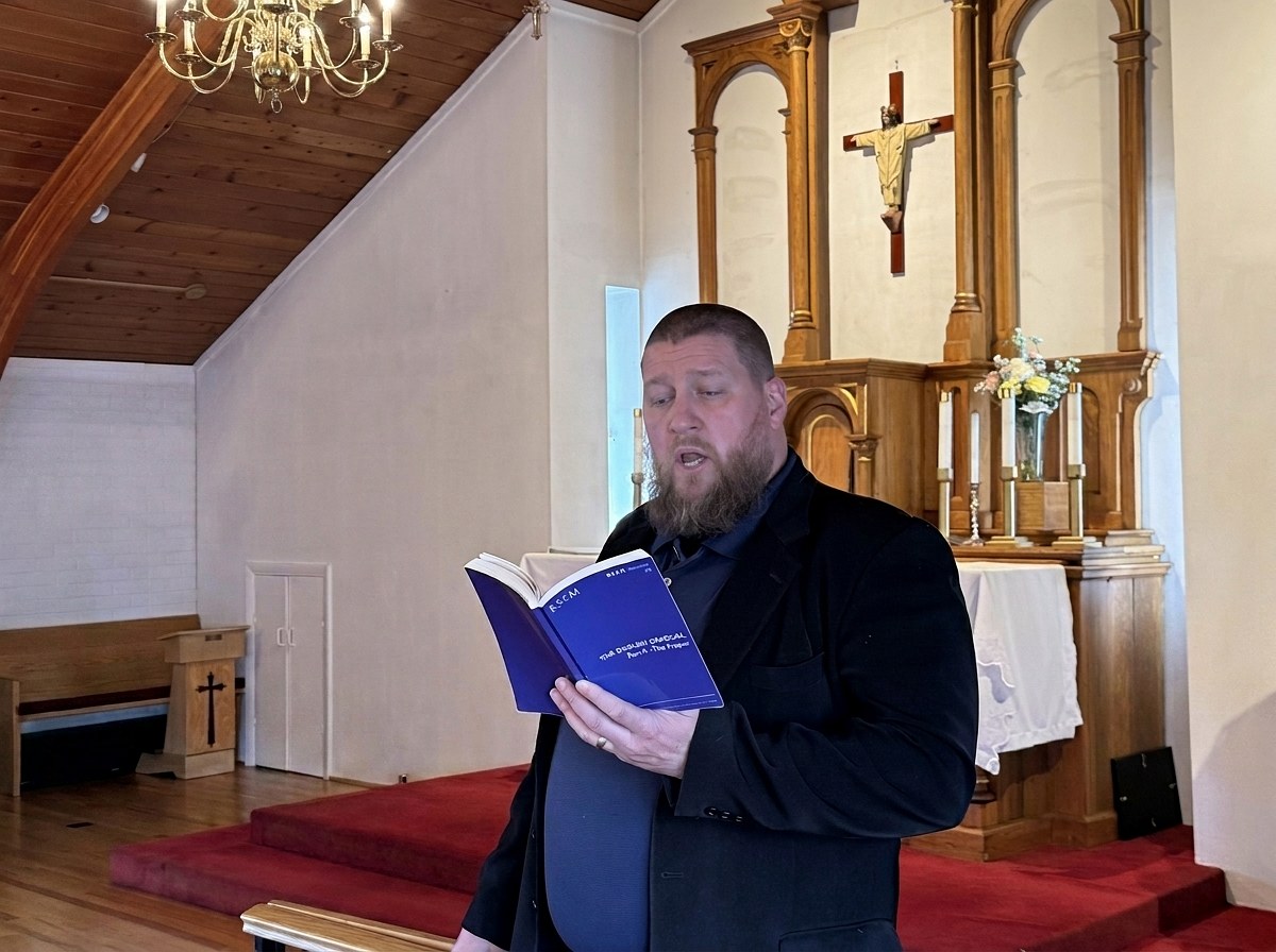 Michael Holmes leading the chant at the front of the nave, chant book in hand